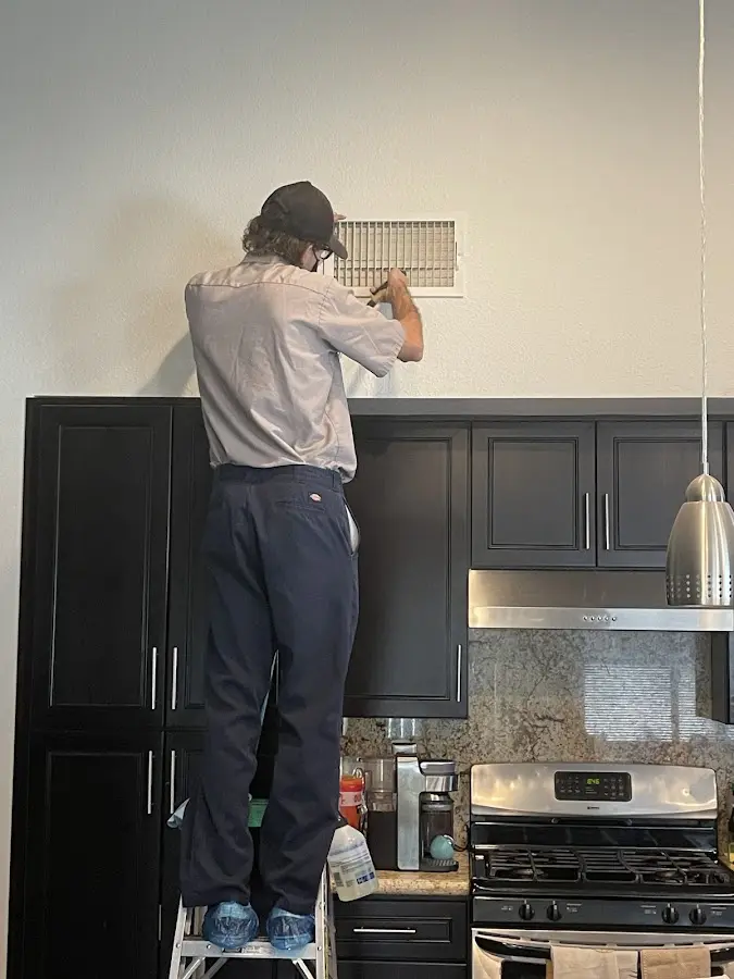 Technician inspecting an air vent during HVAC service in Immokalee